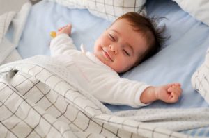 Bébé heureux les bras étendus en train de dormir dans sa chambre de bébé
