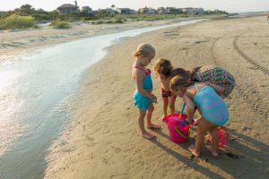 Petites filles en train de remplir un seau sur la plage