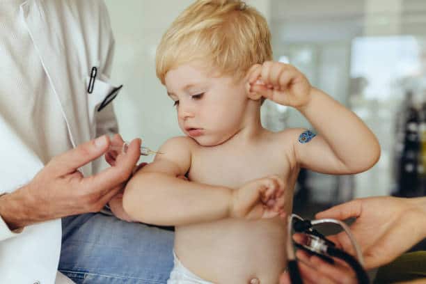 Petit garçon blond en train de se faire vacciner