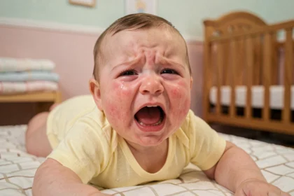 Bébé de 6 à 9 mois en pleine crise de colère, pleurant avec les joues rouges dans une chambre de bébé cosy
