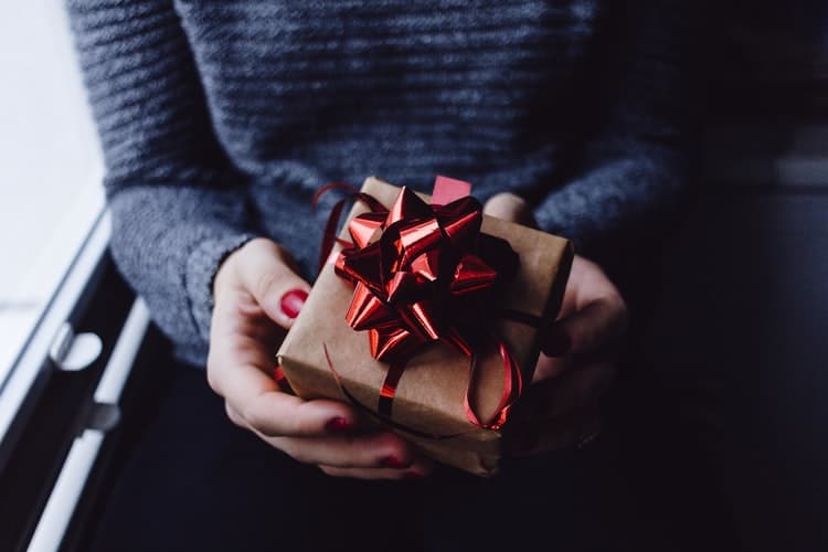 Jeune femme qui tient un cadeau contenant une médaille entre ses mains