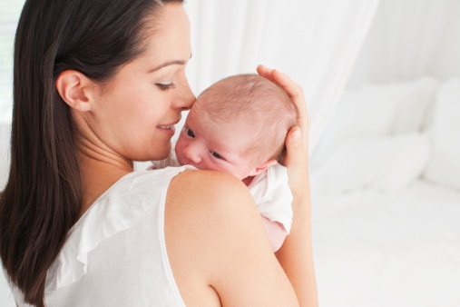 Maman tenant son jeune bébé contre elle pour faire un câlin