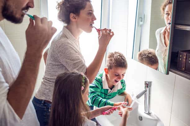 Famille nombreuse qui partage la salle de bain pour se brosser les dents