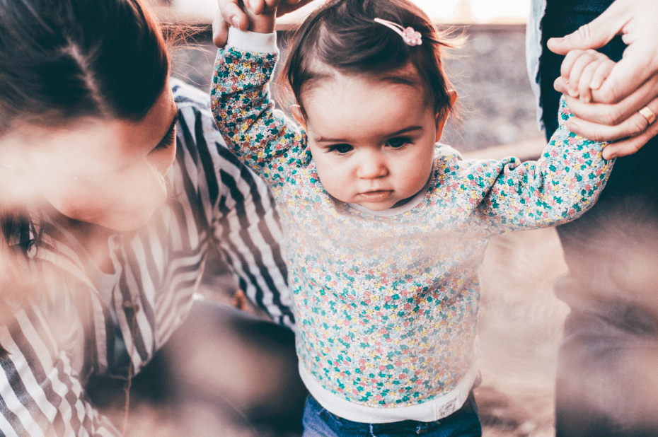 Petite fille apprenant à marcher en tenant les mains de ses parents