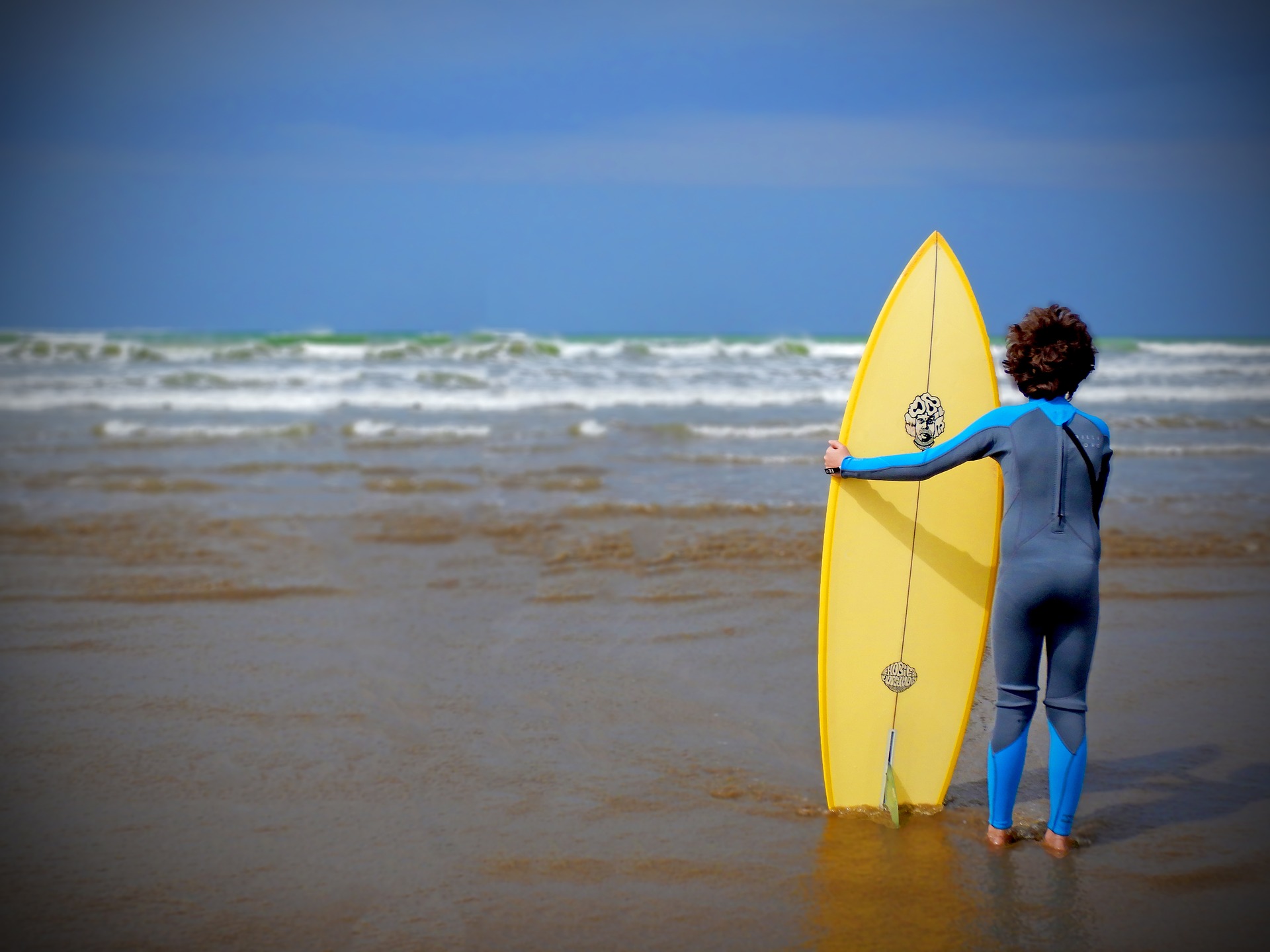 Une petit garçon sur la plage avec un surf