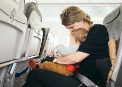 maman assise dans un avion tenant son bébé sur les genoux