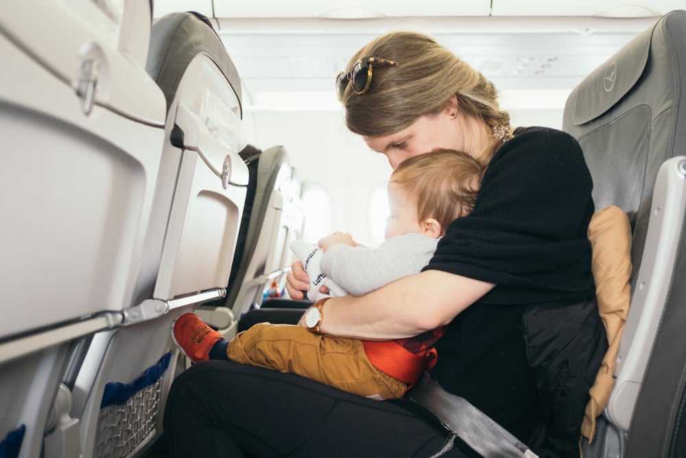 maman assise dans un avion tenant son bébé sur les genoux