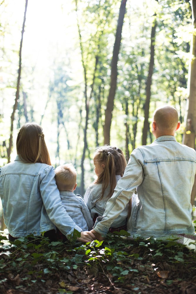 famille de 4 personnes portant ds vestes en jean assise dans une forêt